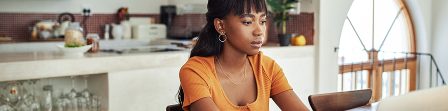 Young Woman Focused on Laptop and Paperwork at Home